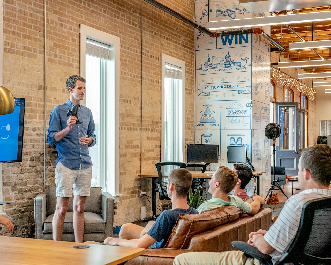Trainer leading a workshop for colleagues in a brick-walled office