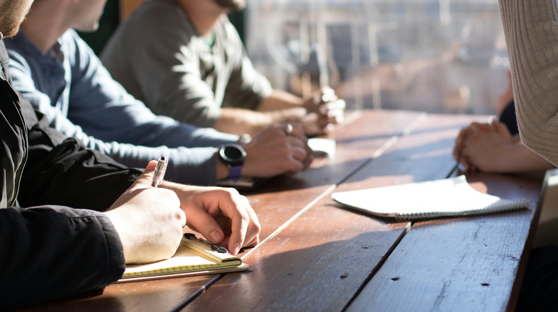 Two people working through notes together at a wooden table