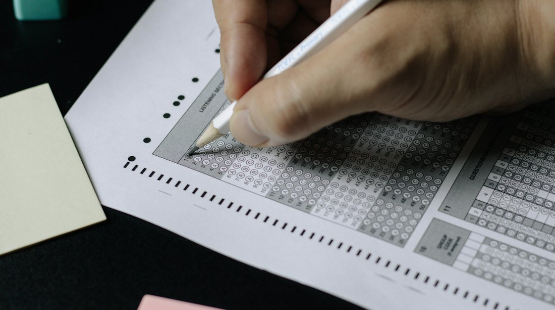 Close-up of a hand filling in a multiple-choice answer sheet