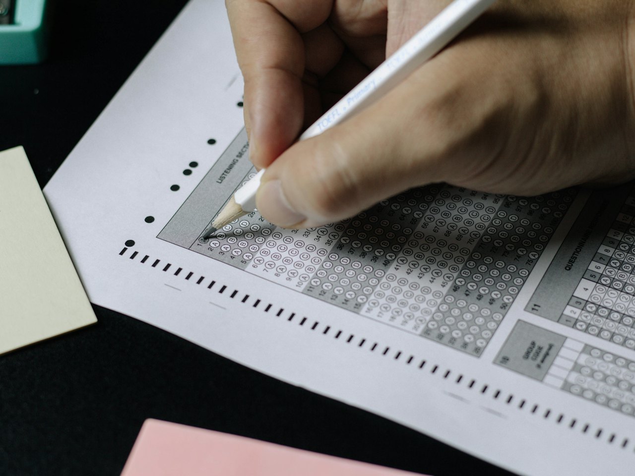Close-up of a hand filling in a multiple-choice answer sheet