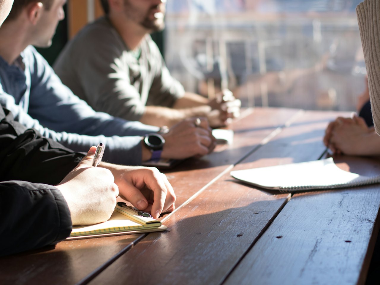 Two people working through notes together at a wooden table