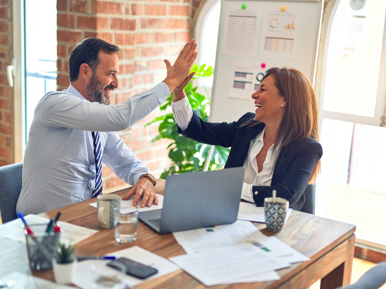 Two colleagues celebrating with a high five at a meeting table