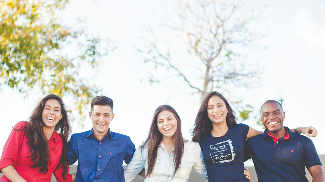 Group of smiling friends sitting together outdoors